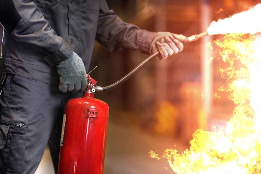 Man using a fire extinguisher to control a fire