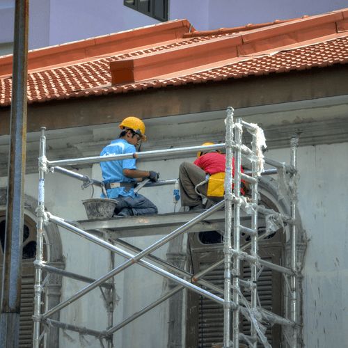 OSHA Scaffolding Safety Training two workers on a scaffold near a building