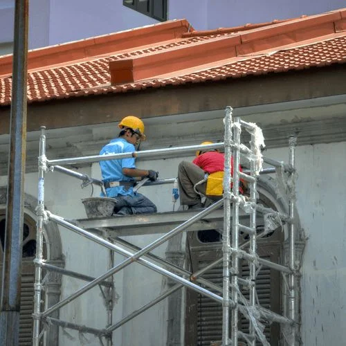 OSHA Scaffolding Safety Training two workers on a scaffold near a building
