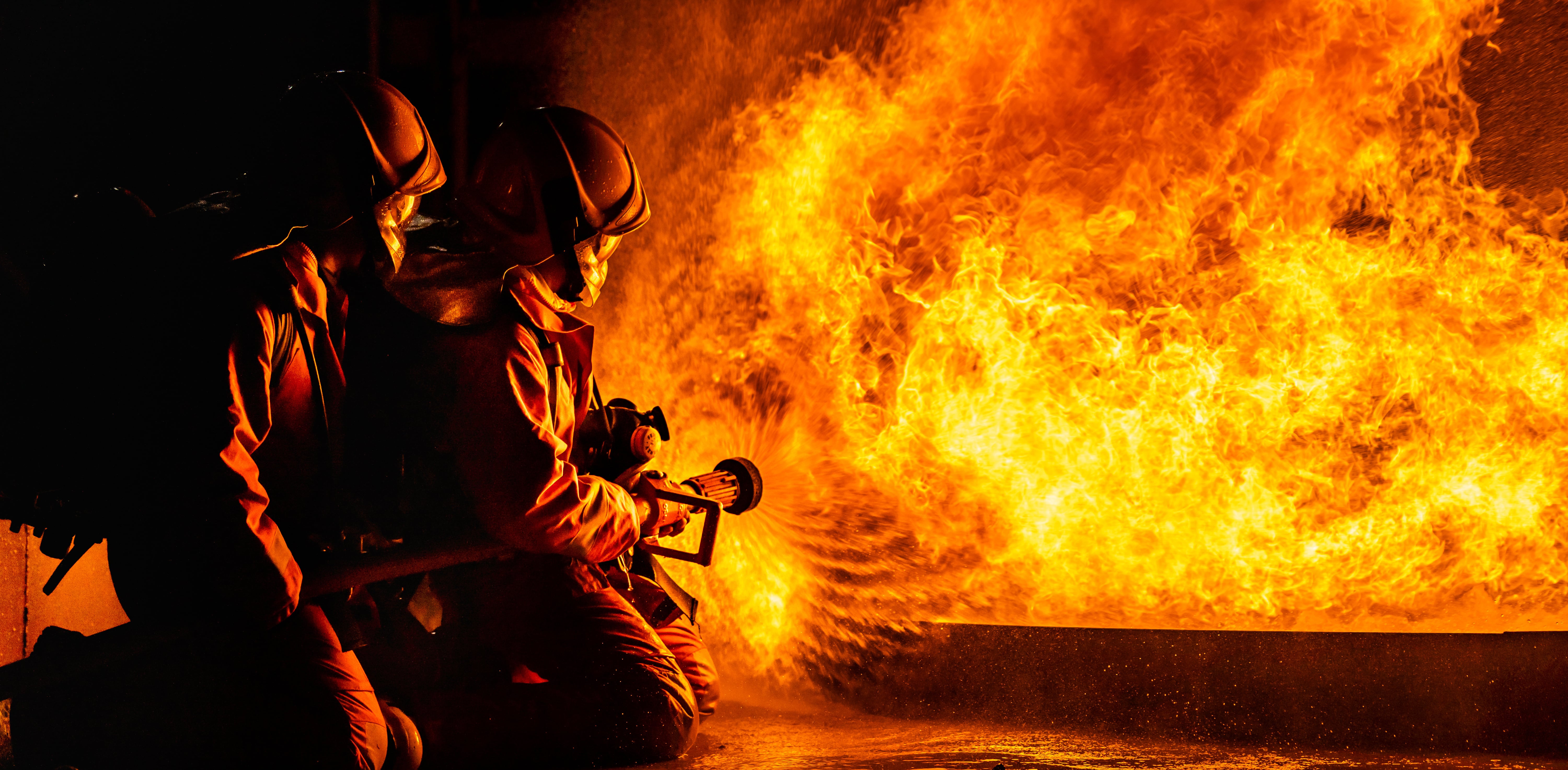 Two firefighters extinguishing a fire at factory